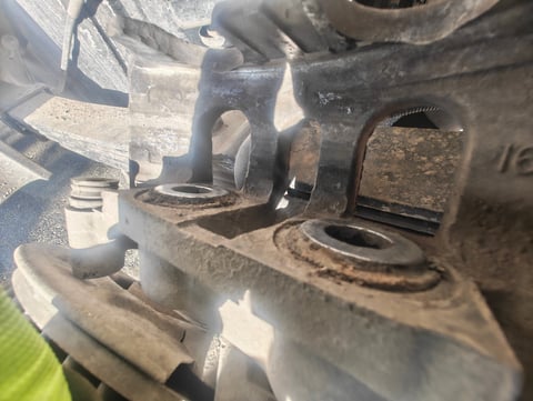 Close-up of dirty engine components showing metal bolts, nuts, and mechanical parts with rust and grime buildup