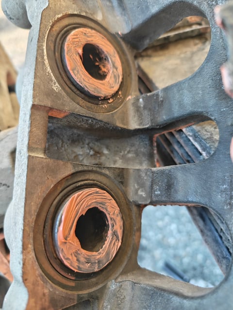 Close-up of weathered metal mechanical part with two circular apertures showing rust and corrosion